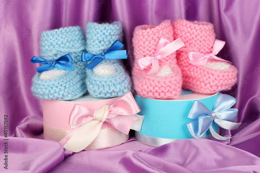 pink and blue baby boots and gifts on silk background.