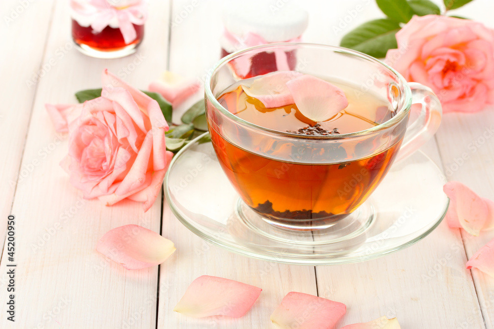 cup of tea with roses and jam on white wooden table cup of tea with roses and jam on white wooden table