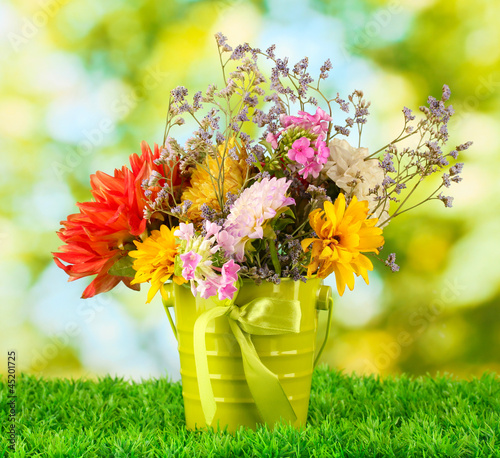 Bright green bucket with flowers on green background
