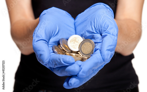 Human hands in medical gloves holding coins