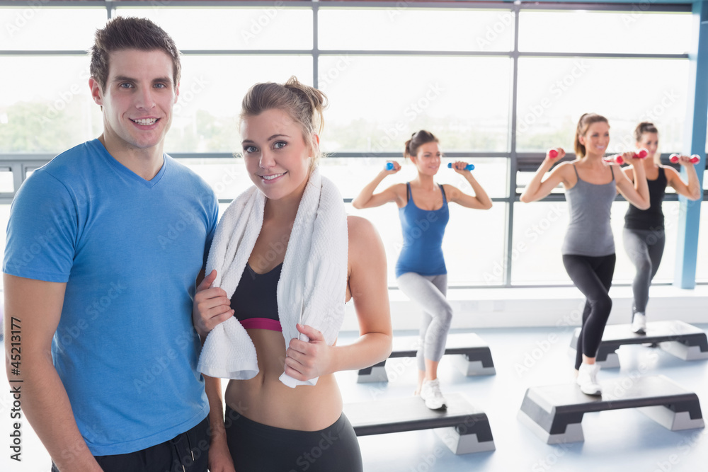 Woman and trainer smiling together in front of aerobics class