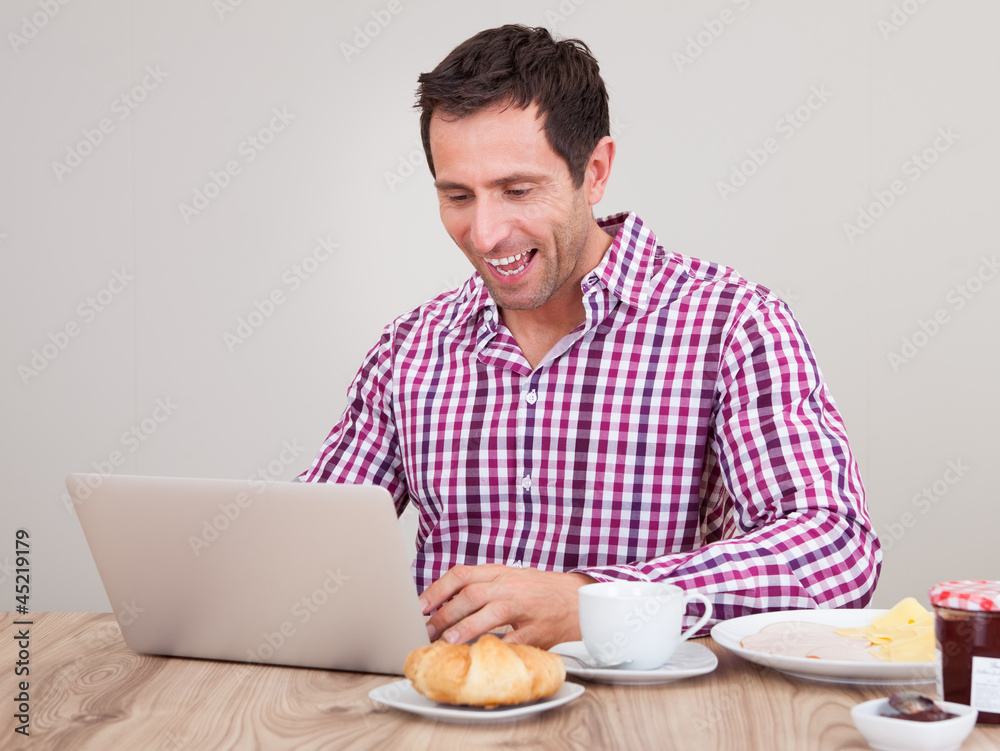 Portrait Of Young Man Using Laptop At Breakfast Portrait Of Young Man Using Laptop At Breakfast