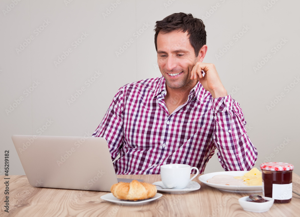 Portrait Of Young Man Using Laptop At Breakfast