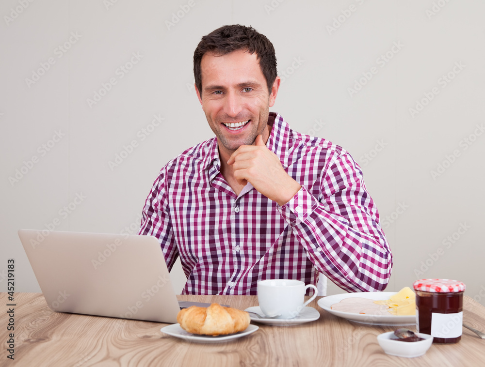 Portrait Of Young Man Using Laptop At Breakfast Portrait Of Young Man Using Laptop At Breakfast