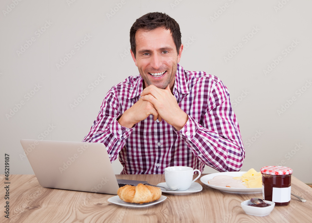 Portrait Of Young Man Using Laptop At Breakfast Portrait Of Young Man Using Laptop At Breakfast