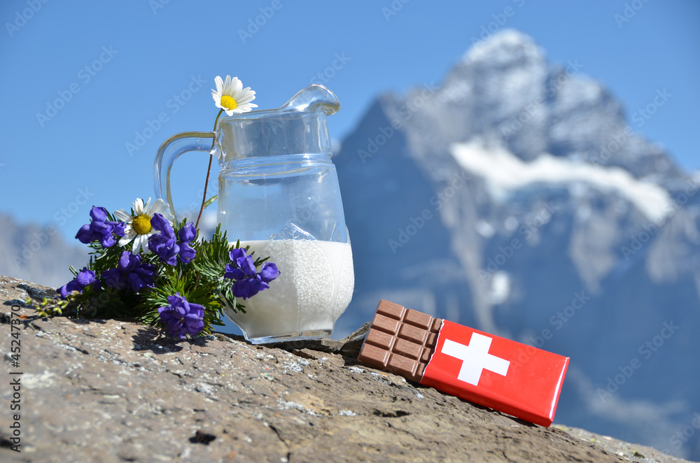 Swiss chocolate, jug of milk and Apline flowers. Switzerland