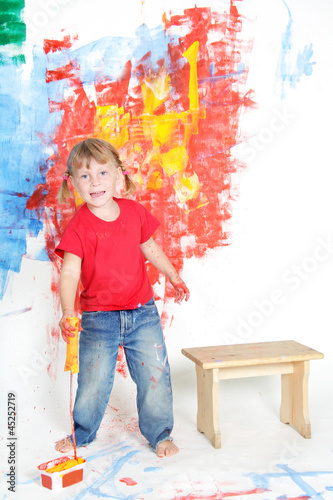 young happy child girl painting white wall with colours © Alena Yakusheva