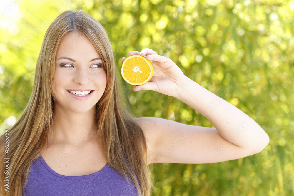 Hübsche Frau draußen mit Orangenscheibe Hübsche Frau draußen mit Orangenscheibe