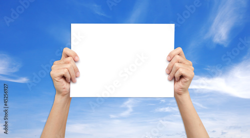 Hands holding paper over the sky