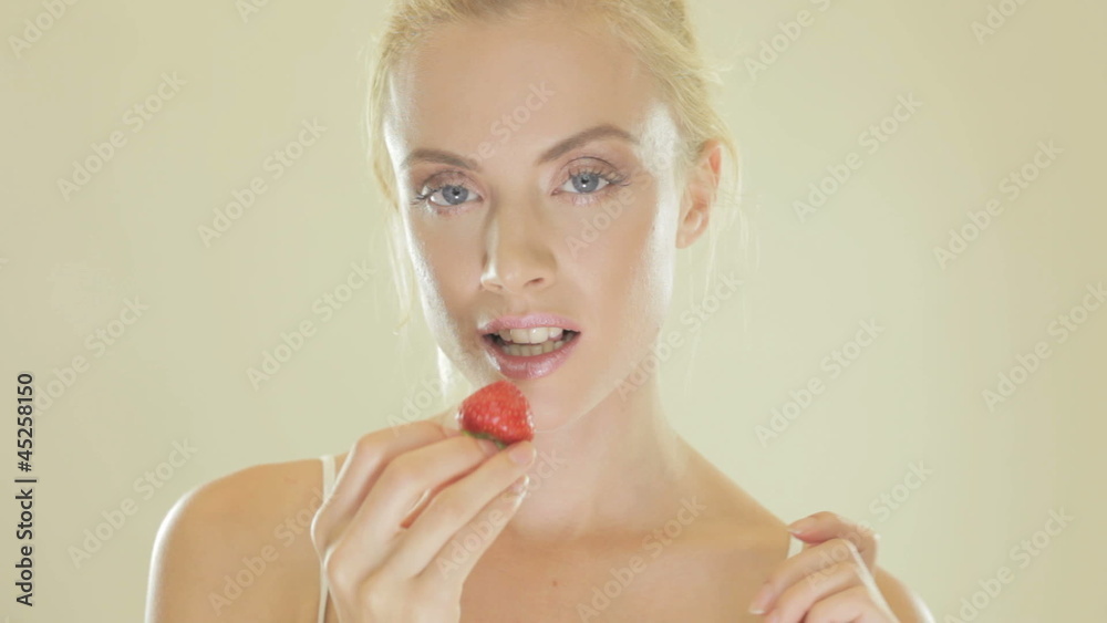Attractive blonde woman eating a strawberry Attractive blonde woman eating a strawberry