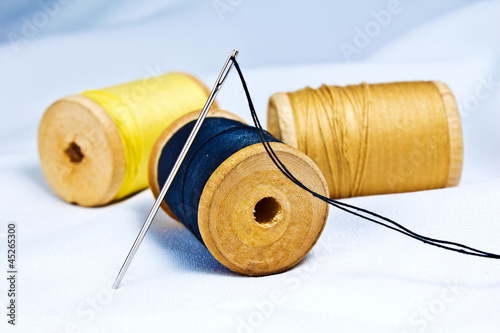 Spool of thread and needle on fabric.