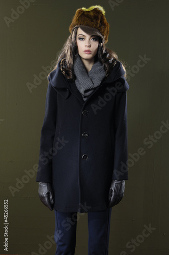 young fashion model in gloves posing on dark background
