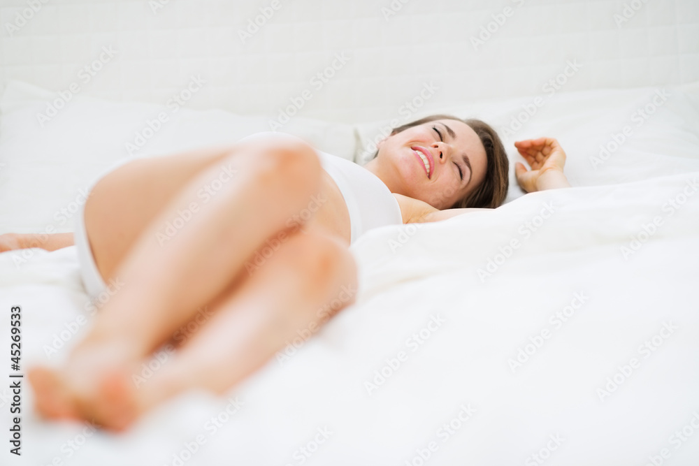 Obraz premium Happy young woman laying on bed