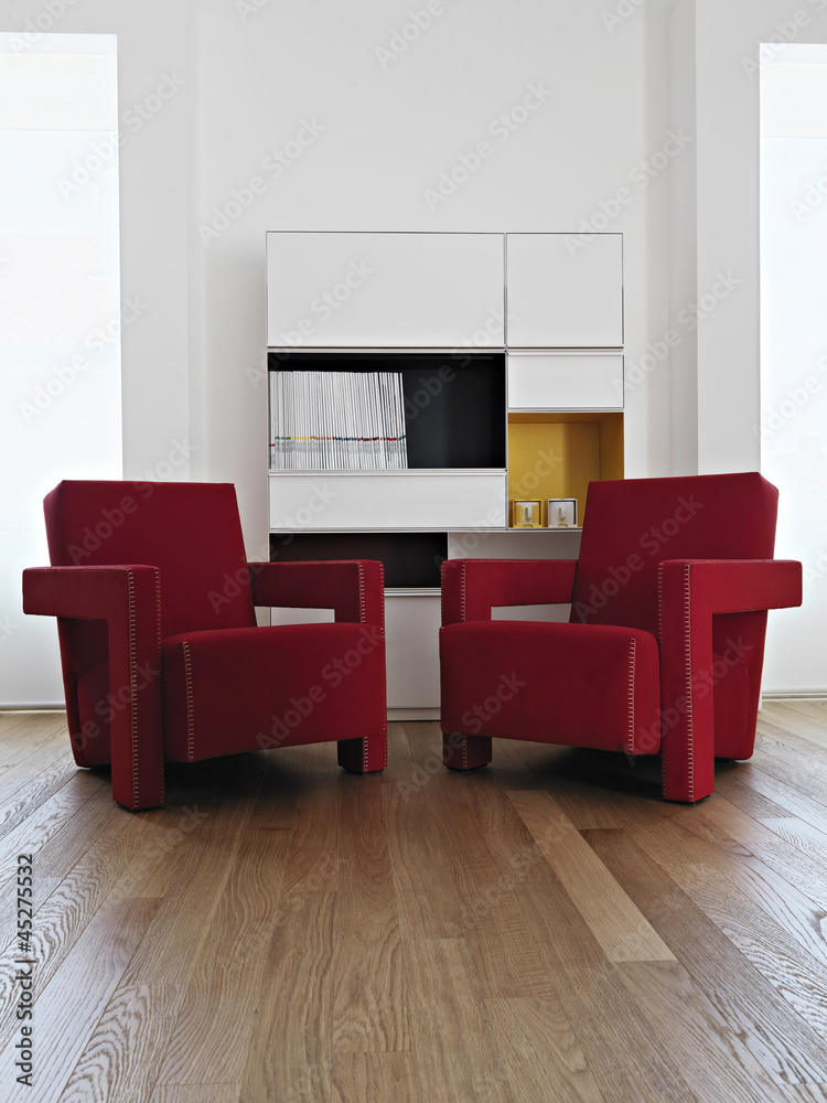 Foto Stock due moderne poltrone rosse in soggiorno col parquet | Adobe Stock