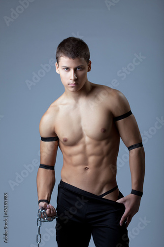 athletic man dance striptease with chain