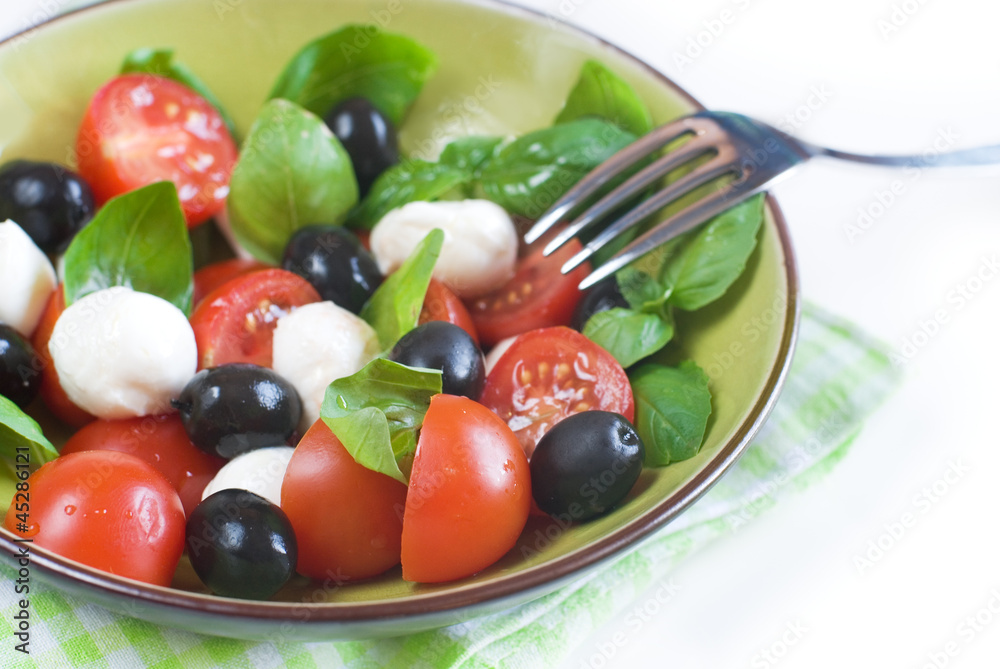 Salad with tomatoes, mozarella, olives and basil