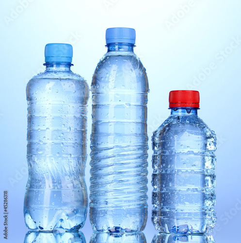 plastic bottles of water on blue background © Africa Studio