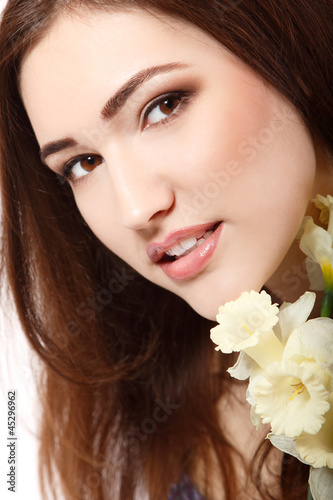 beautiful teen girl smiling and with flower narcissus and lookin