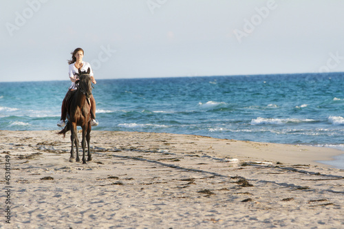 young happy woman with horse on sea background