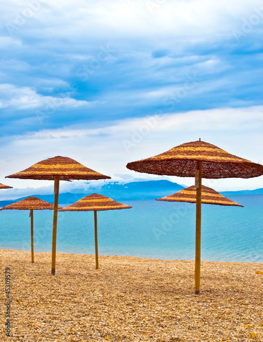 Fototapeta Naklejka Na Ścianę i Meble -  A straw umbrella on a tropical beach with blue sky