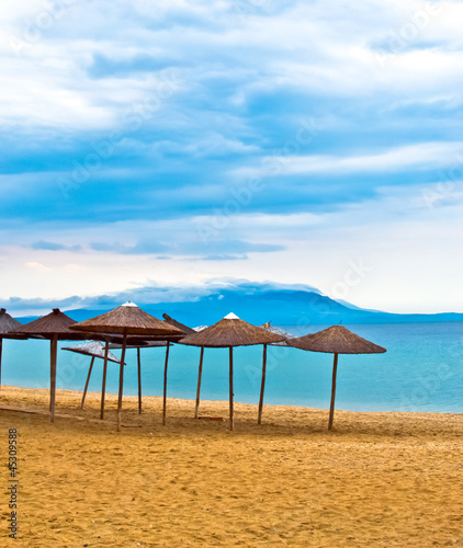 A straw umbrella on a tropical beach with blue sky © vician_petar