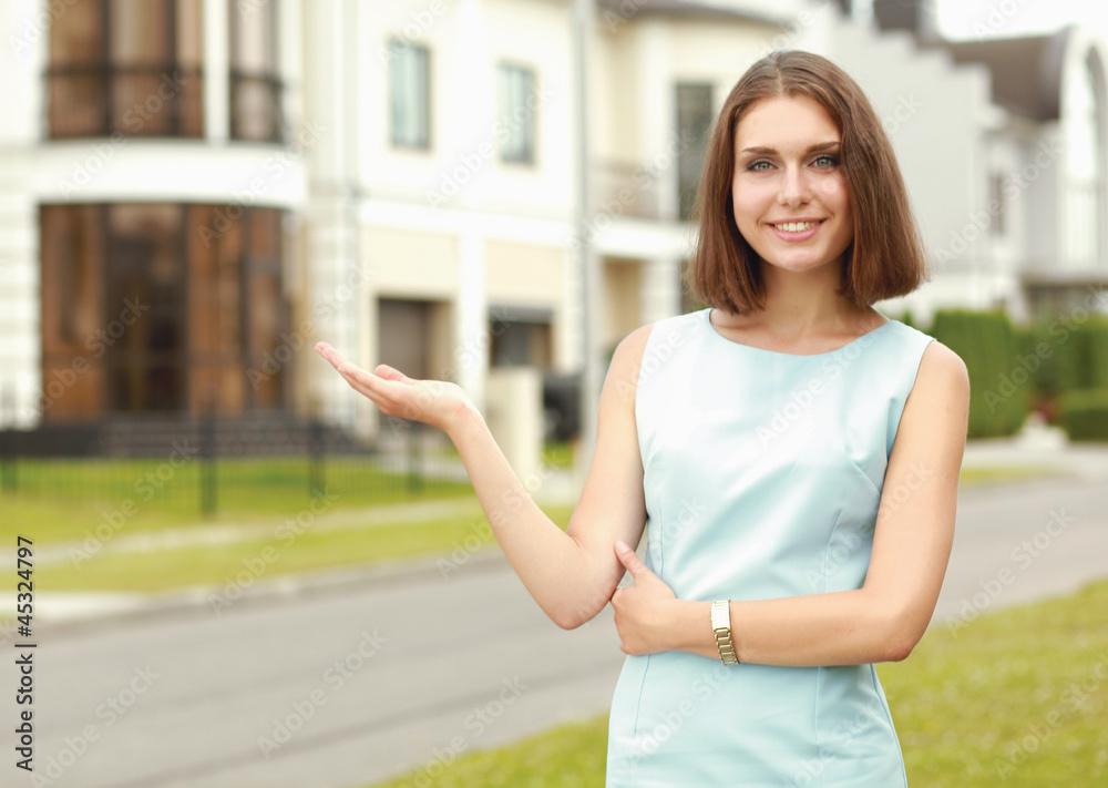 A young woman pointing at something near house