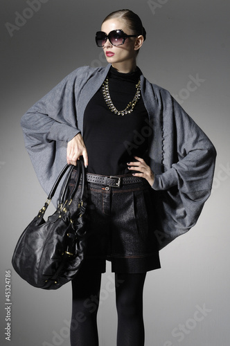 High fashion model with bag posing in light the studio