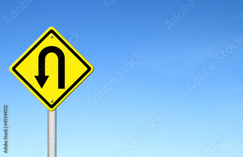Yellow warning sign u-turn roadsign with blue sky background