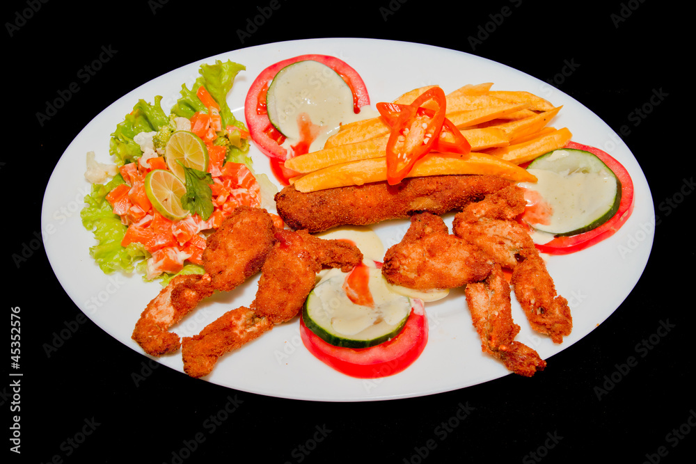 fried frogs legs on a plate isolated in black fried frogs legs on a plate isolated in black