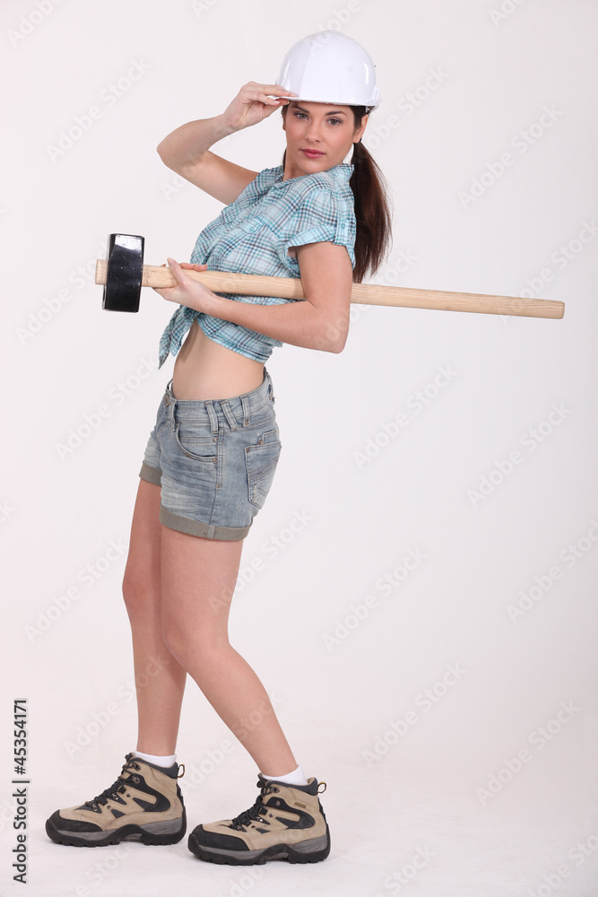 A female construction worker with a sledgehammer. A female construction worker with a sledgehammer.