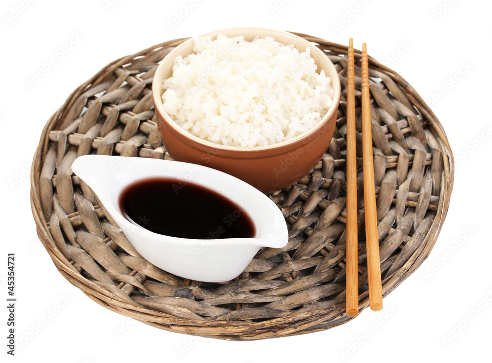 Bowl of rice and chopsticks on wicker mat isoalted on white