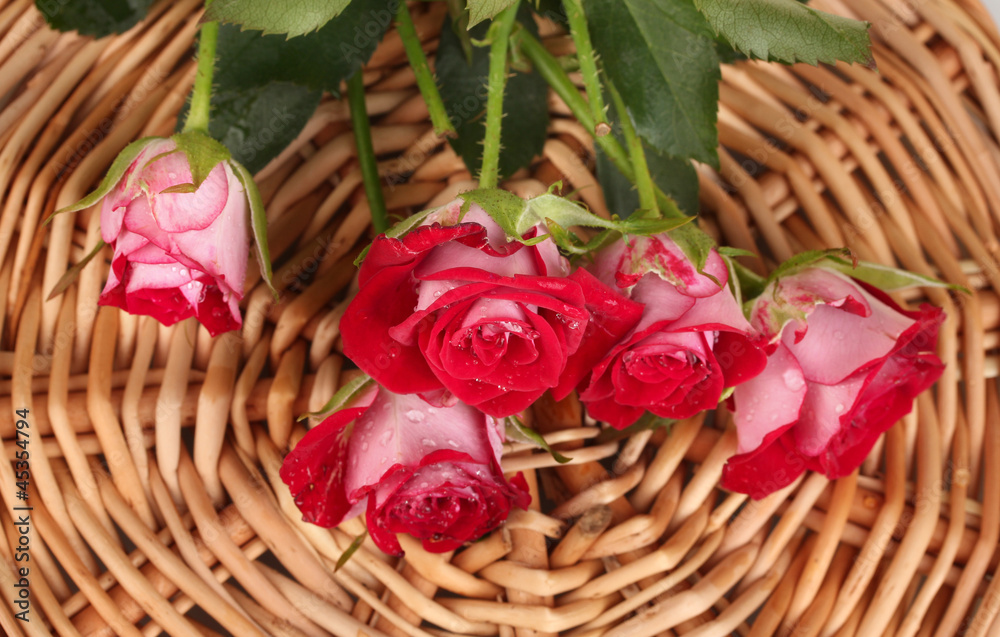 Beautiful vinous roses on wicker mat close-up