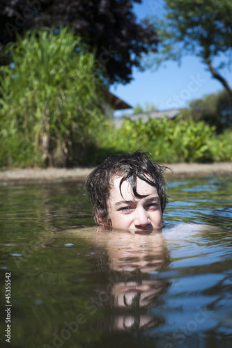 young boy looks with his eyes out of a lake 