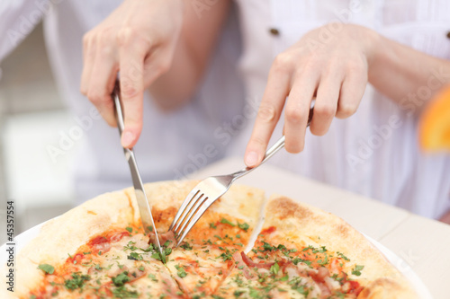 Fototapeta Naklejka Na Ścianę i Meble -  Cutting a  pizza with knife