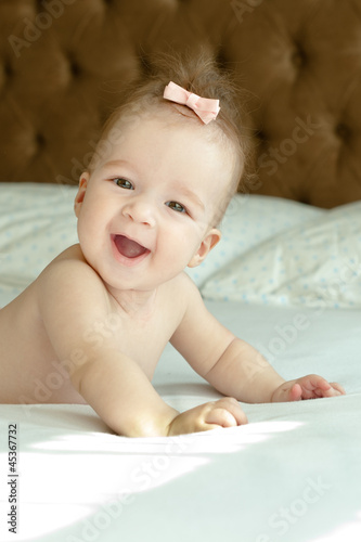 six month smiling baby girl laying on the bed