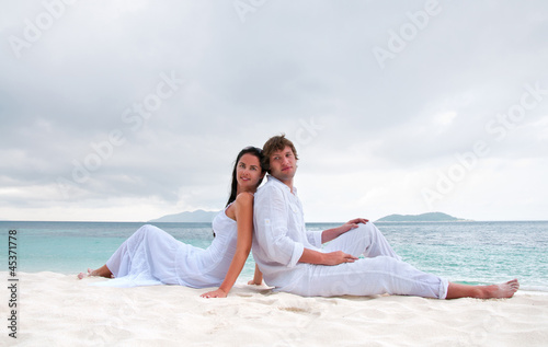 Young couple sitting on the beach near the seaside © Dmitrijs Dmitrijevs