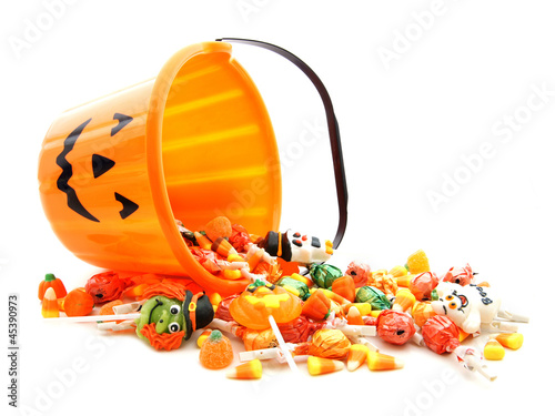 Halloween jack-o-lantern pail with spilling candy over white