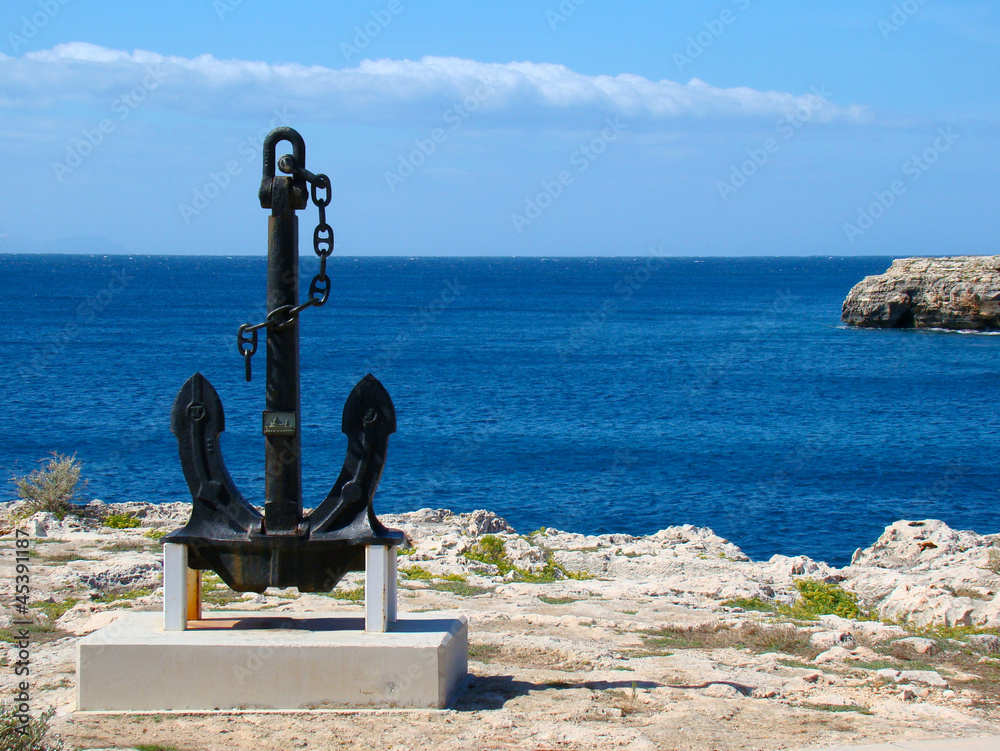 A big black anchor located on the coast