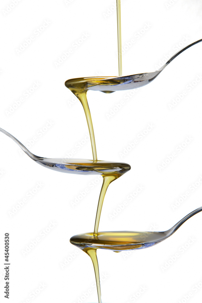 Chorro de aceite de oliva escurriendo de una cuchara a otra Chorro de aceite de oliva escurriendo de una cuchara a otra