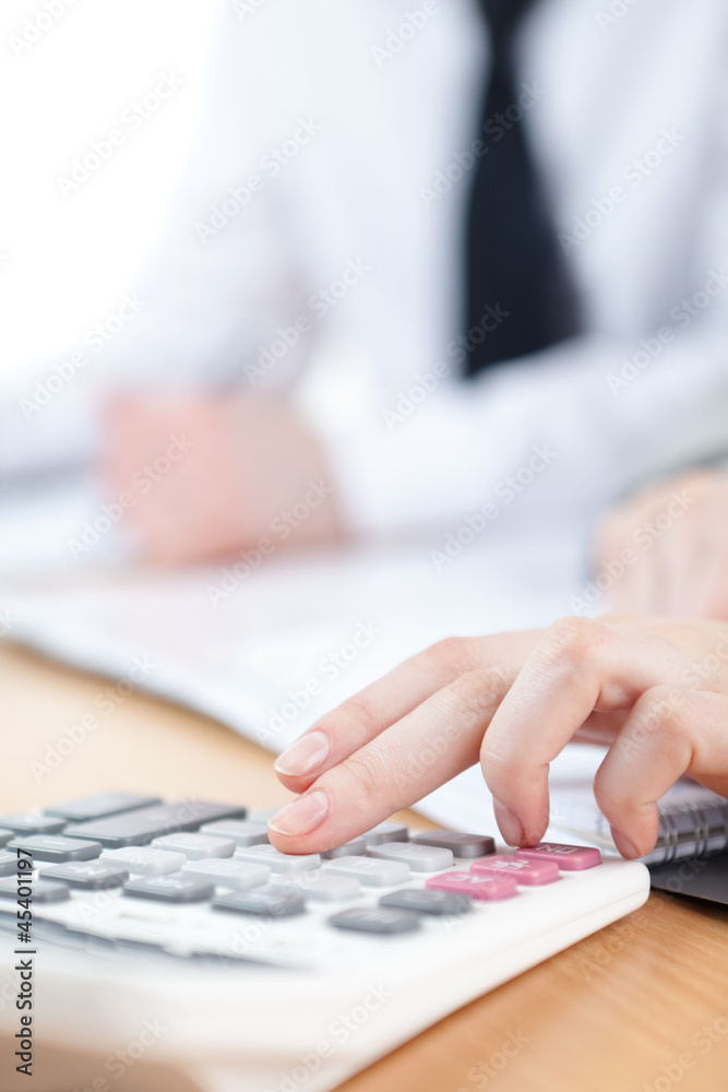 Manager counting on calculator sitting at the table Manager counting on calculator sitting at the table