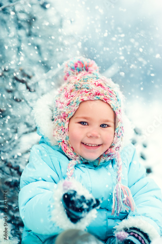 portrait of a little girl in winter hat in snow forest at showfl
