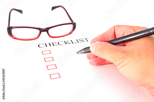 Checklist with pen, glasses and checked boxes.
