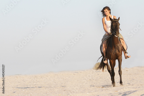 young happy woman riding horse on natural background