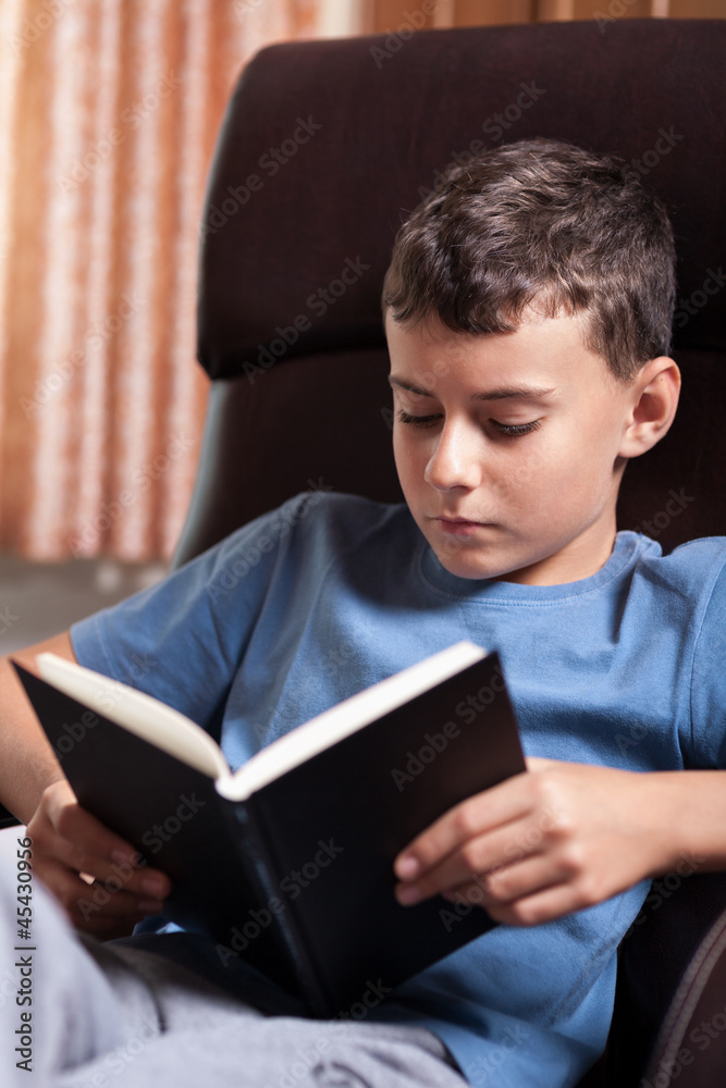 Child reading a book, sitting in an armchair Child reading a book, sitting in an armchair