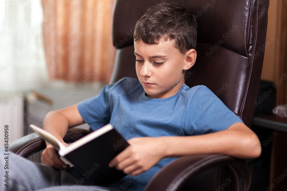 Child reading a book, sitting in an armchair Child reading a book, sitting in an armchair