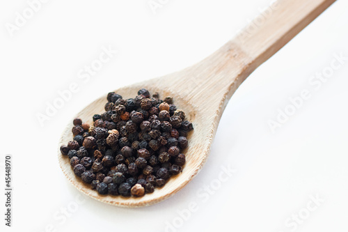 Black peppercorns in wooden spoon