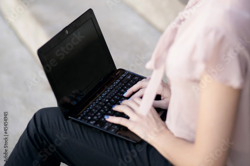 junge Frau sitzt mit Laptop draußen