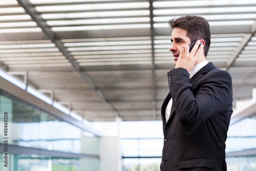 Young business man talking on cell phone at modern office Young business man talking on cell phone at modern office
