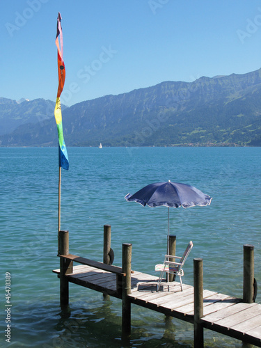 Chair and umbrella on a wooden pier at the lake Thun, Switzerlan