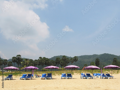 Row of umbrellas and sunbeds at a tropical beach © HappyAlex